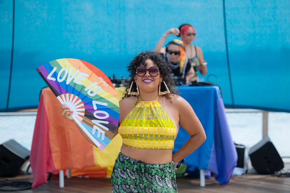 Guest holding pride fan in front of DJs at Navy Pier Pride